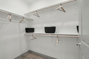 A walk in closet with shelves and hangers on the wall